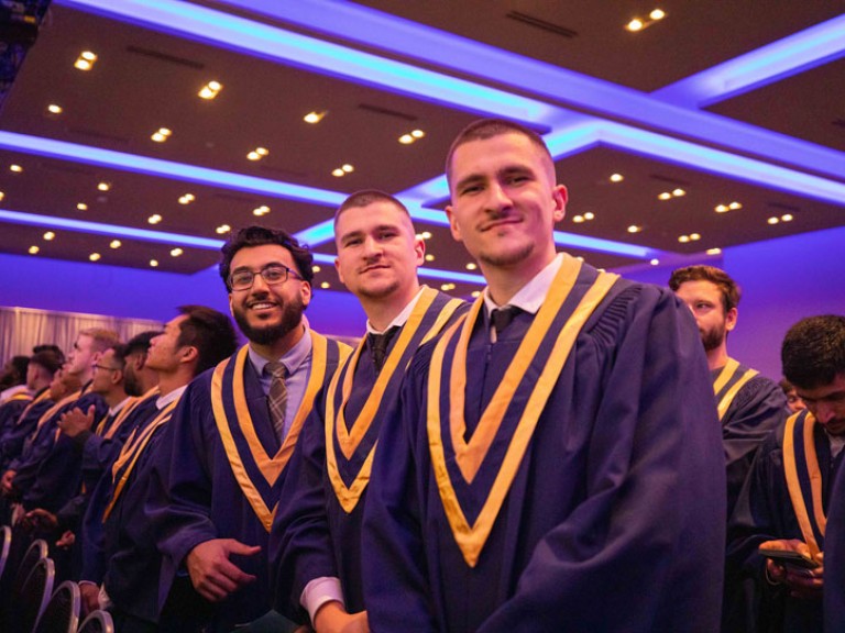 Three graduates in audience pose for photo