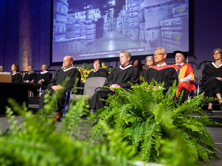 Faculty and honorary degree recipient seated on stage
