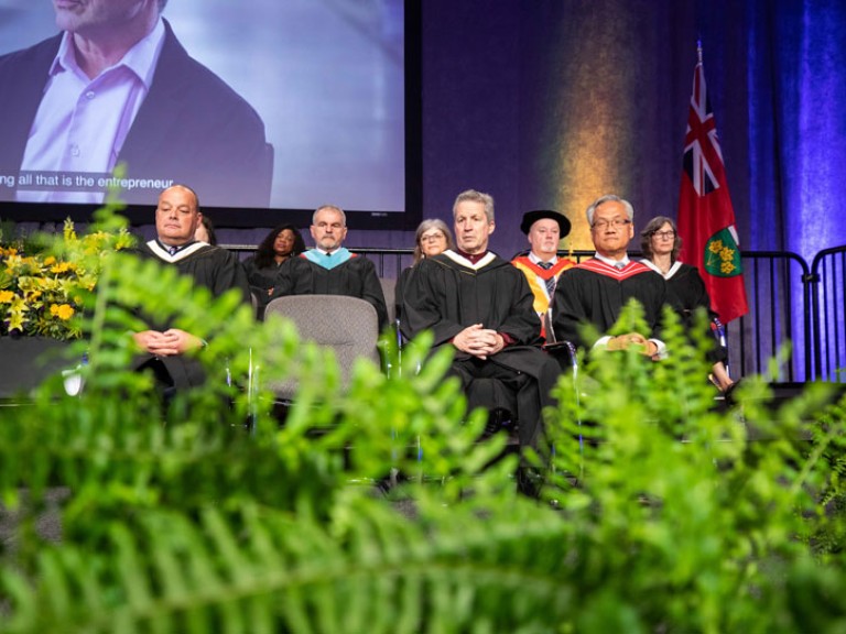 Jim Estill seated on stage with faculty