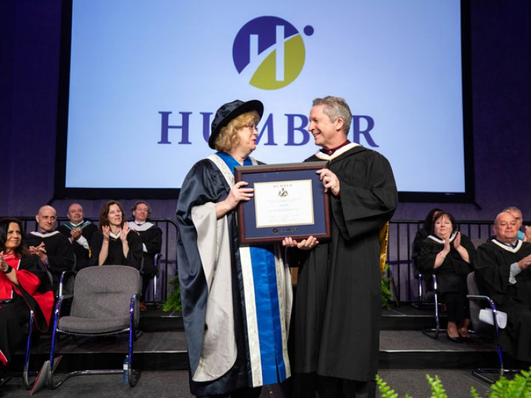 Honorary degree recipient Jim Estill holds framed degree with Humber president Ann Marie Vaughan
