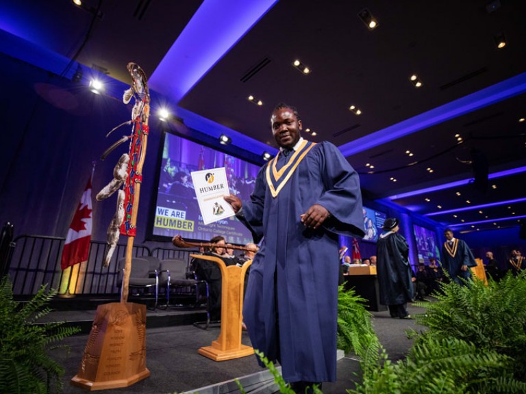 Graduate leaving stage with their congratulations paper