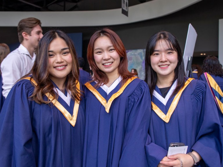 Three graduates smile for camera