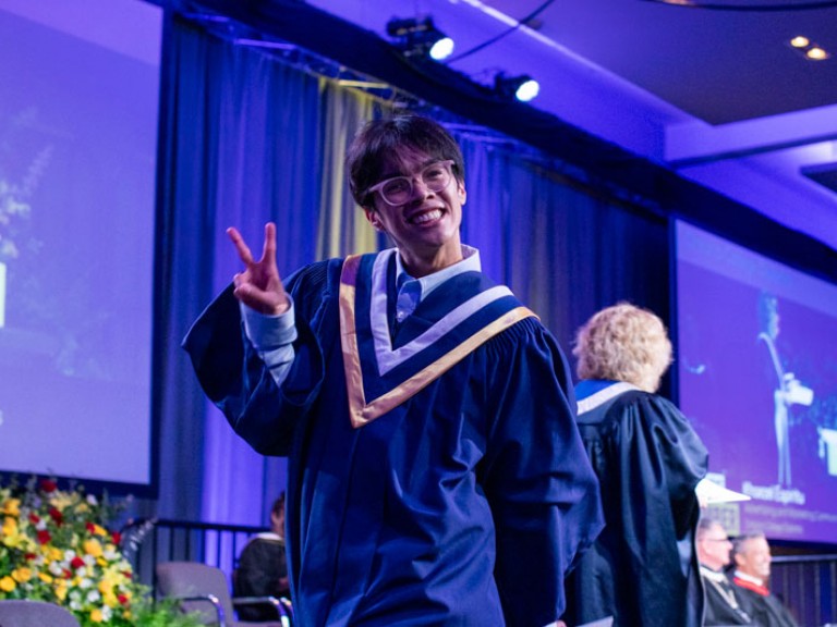 Graduate exits stage making a peace sign
