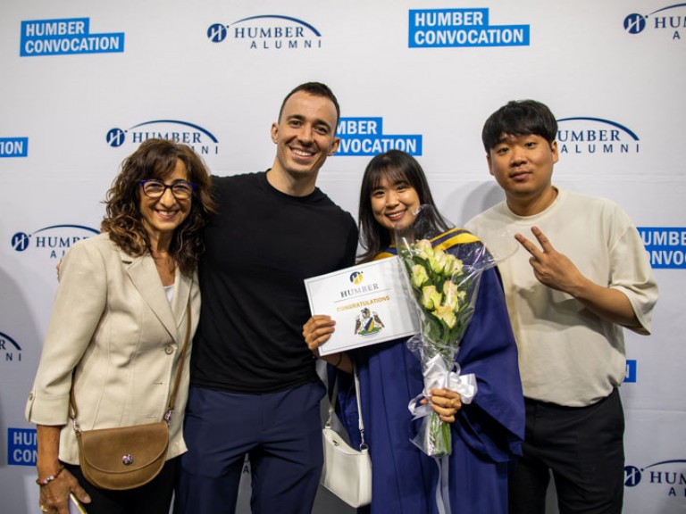 Graduate poses with three ceremony guests