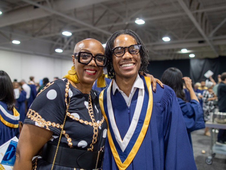 Graduate smiles with family member for photo