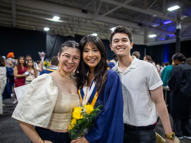 Graduate poses with two ceremony guests