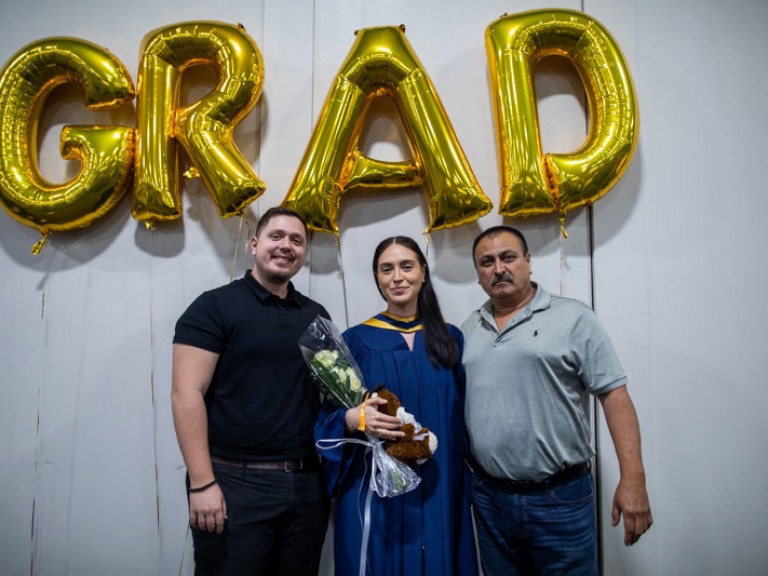 Graduate poses with two family members