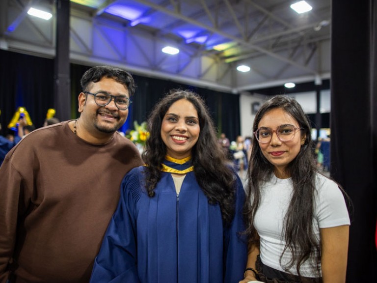 Graduate smiles for camera with two ceremony guests
