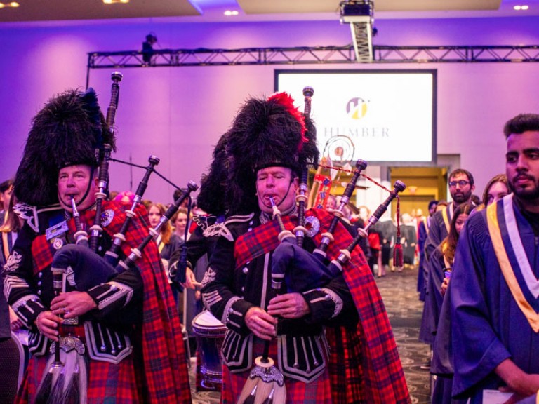 Two bagpipe players in kilts