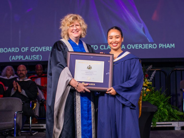 Humber president Ann Marie Vaughan holding award with graduate