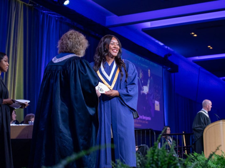 Graduate on stage smiles at audience