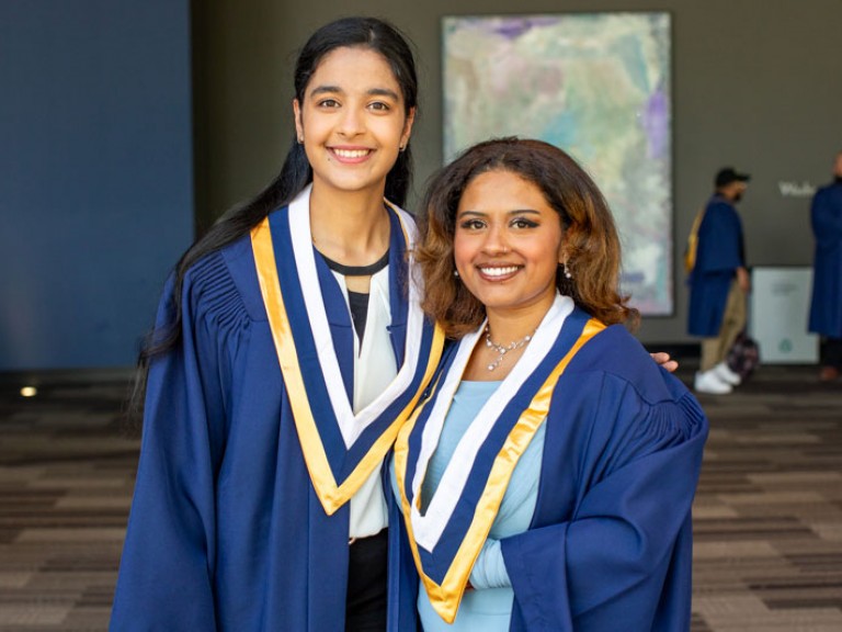 Two graduates smile for camera