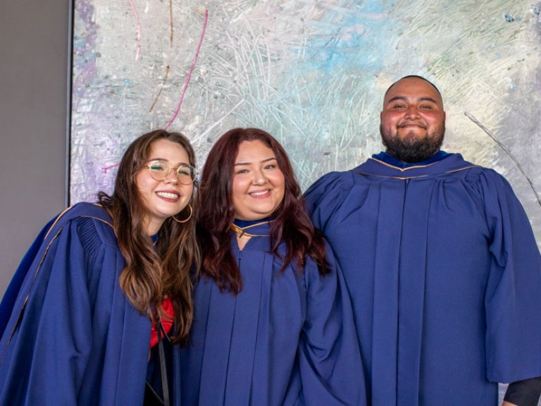 Three graduates smile for photo