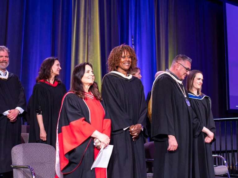 Staff and honorary degree recipient stand on stage