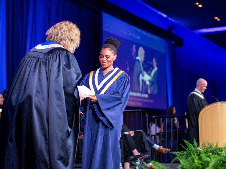 Graduate on stage receives certificate from Ann Marie Vaughan