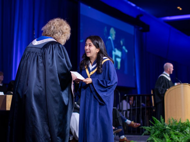 Graduate on stage accepts certificate from Humber president