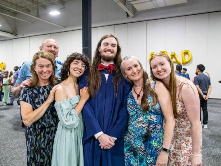 Graduate takes photo with five ceremony guests