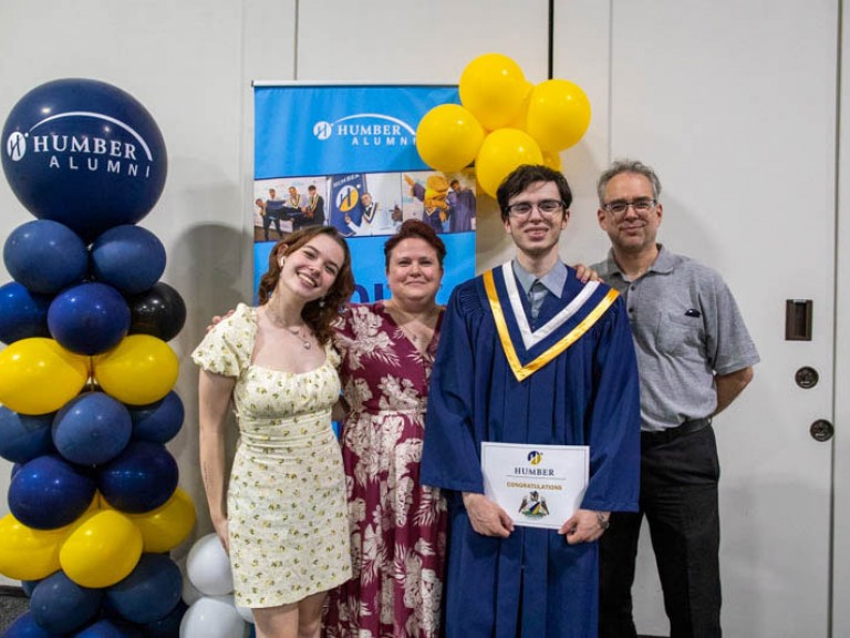 Graduate takes photo with three ceremony guests