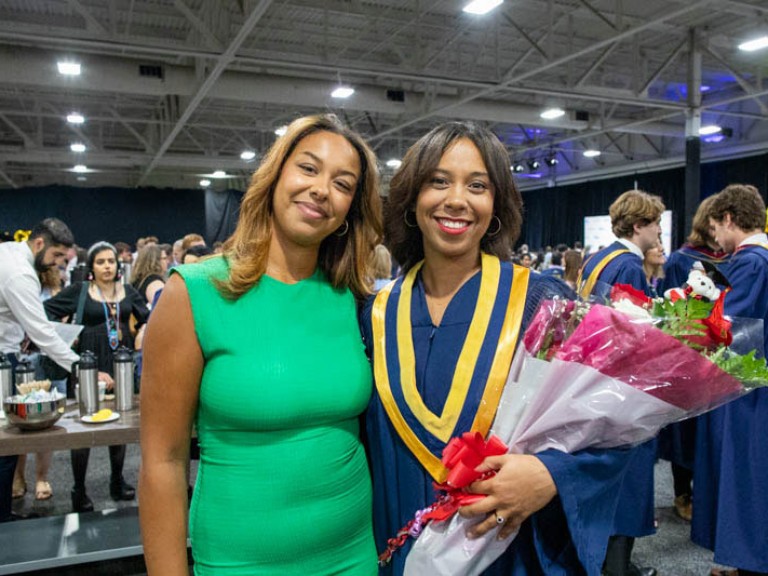 Graduate holding roses takes photo with ceremony guest