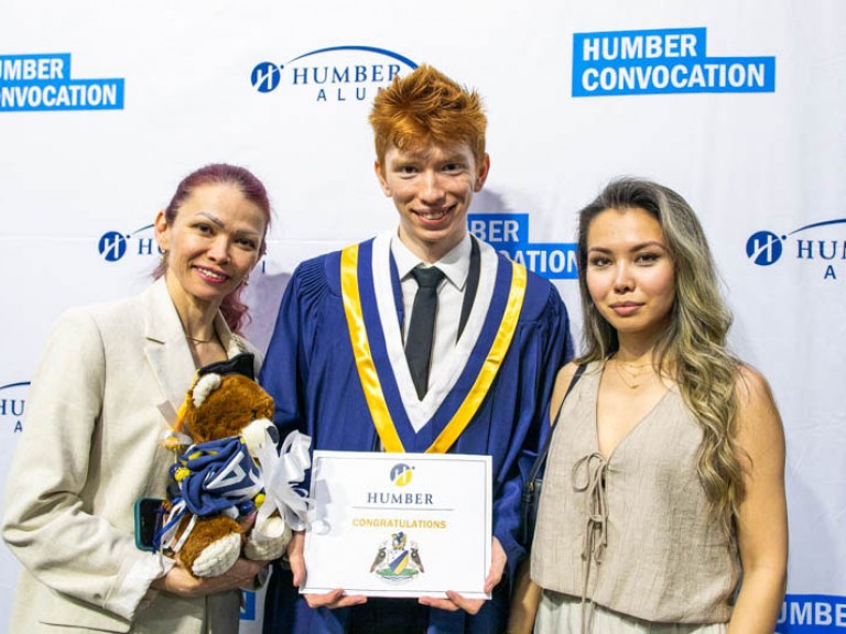 Graduate takes photo with two ceremony guests