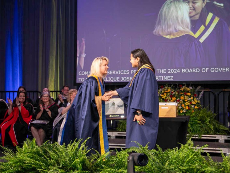 Graduate shakes hand of Humber faculty member on stage