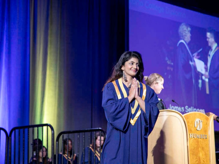 Graduate leaving stage makes prayer sign with her hands