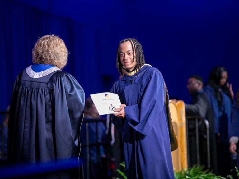 Graduate holds their certificate on stage