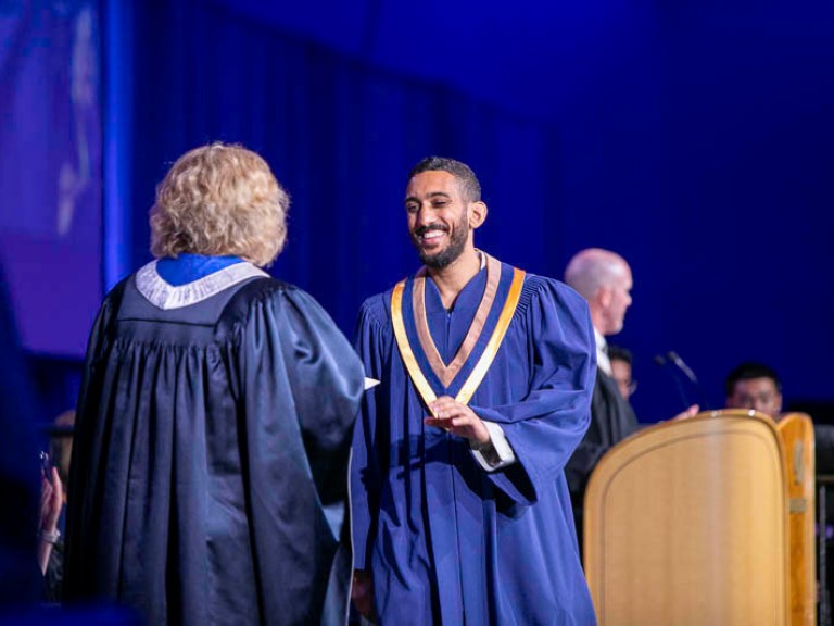 Graduate smiles as they accept their credential