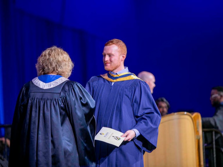 Graduate accepts their credential from Humber president