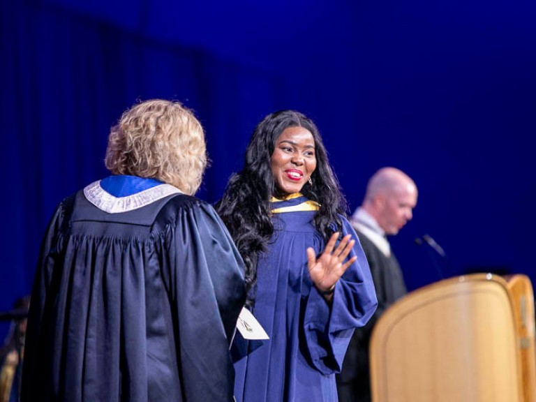 Graduate on stage waves at audience