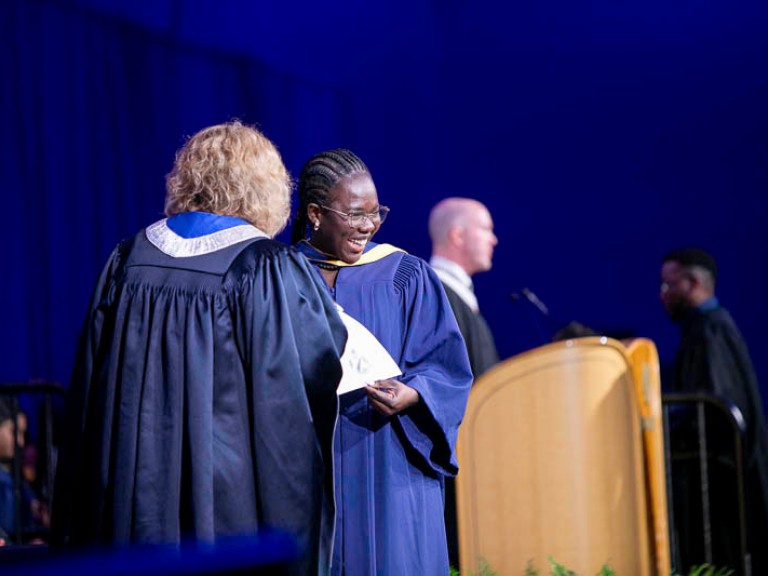 Graduate on stage smiles at audience