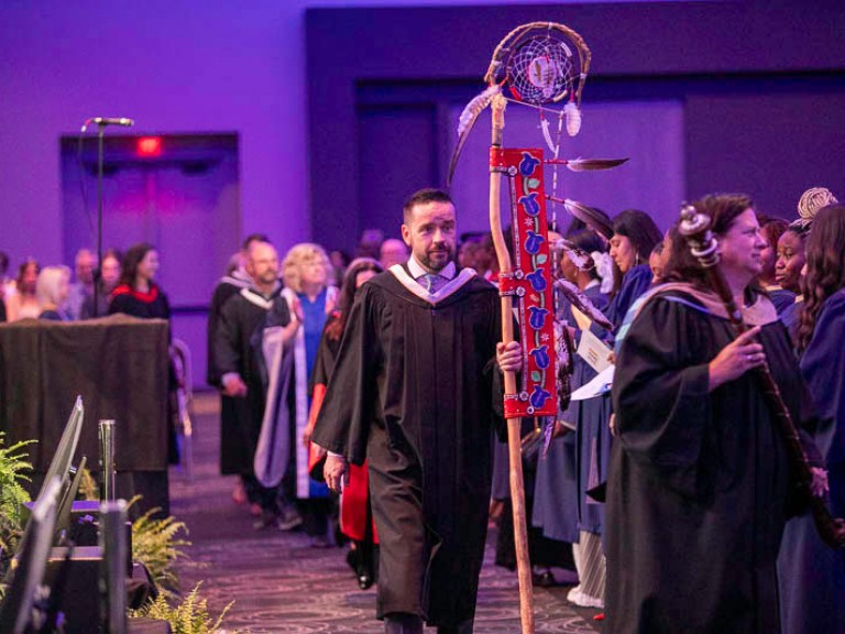 Humber faculty member holding ceremonial Indigenous staff