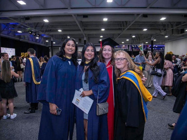 Two graduates and two faculty members take photo