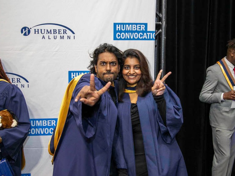 Two graduates hold out peace signs
