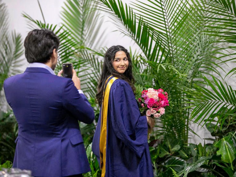 Graduate getting her photo taken by a ceremony guest