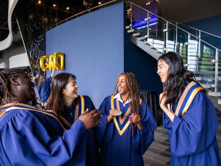 Four graduates smiling at each other