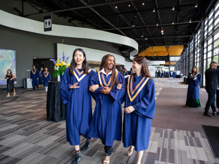 Three graduates walking arm in arm