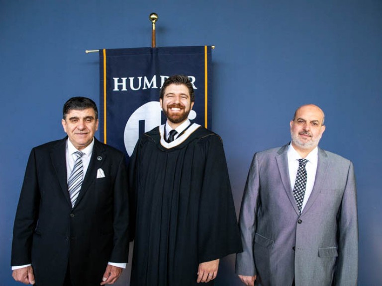 Honorary degree recipient Tareq Hadhad takes photo with two ceremony guests