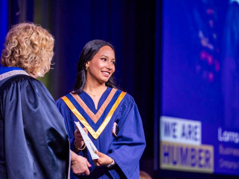 Graduate accepts certificate from Humber president
