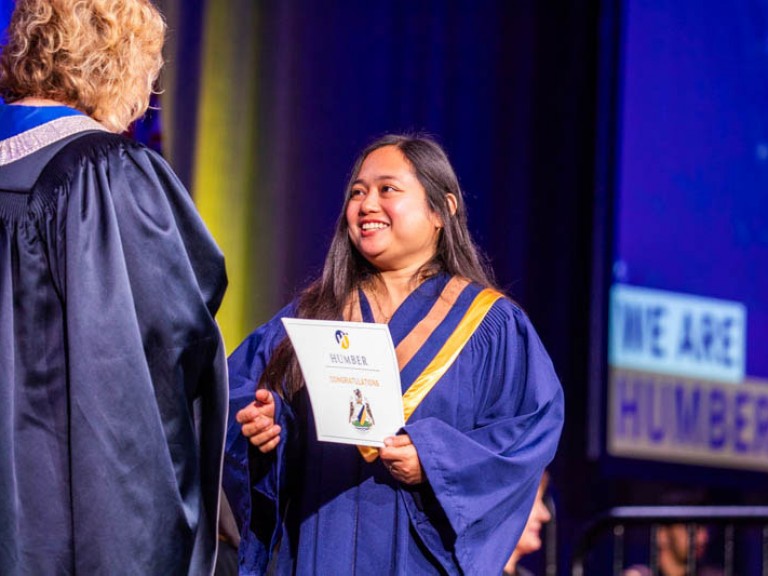 Graduate accepts certificate on stage from Humber president