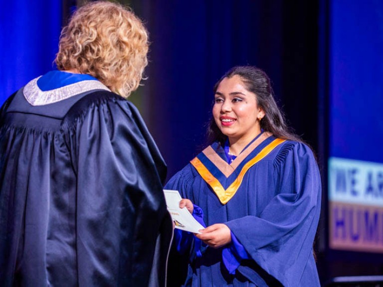 Graduate accepts certificate on stage from Humber president