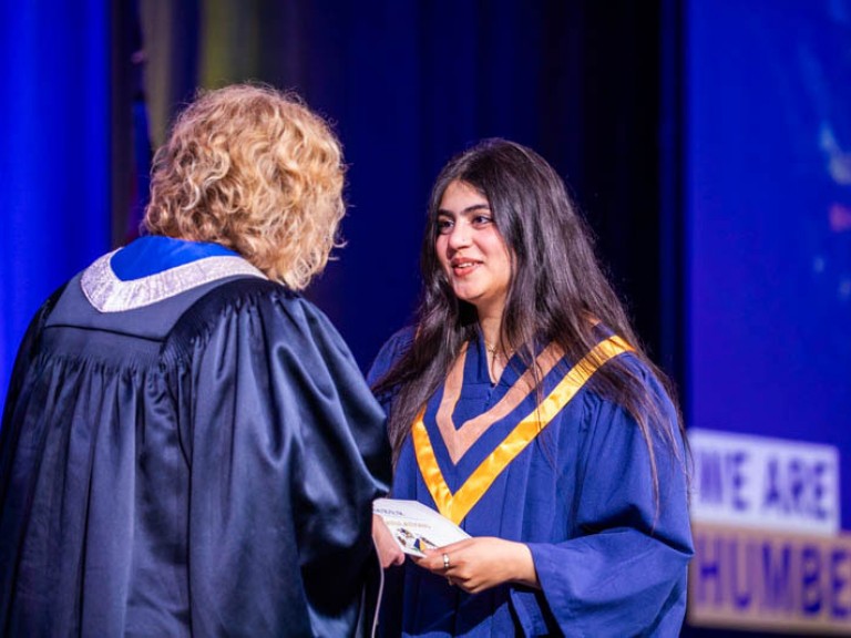 Graduate accepts their certificate on stage