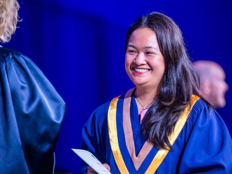 Graduate accepts their certificate with a smile