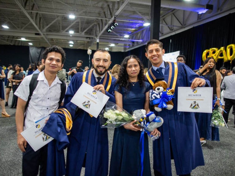 Three graduates take photo with a guest