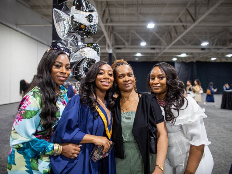 Graduate poses with three others for photo