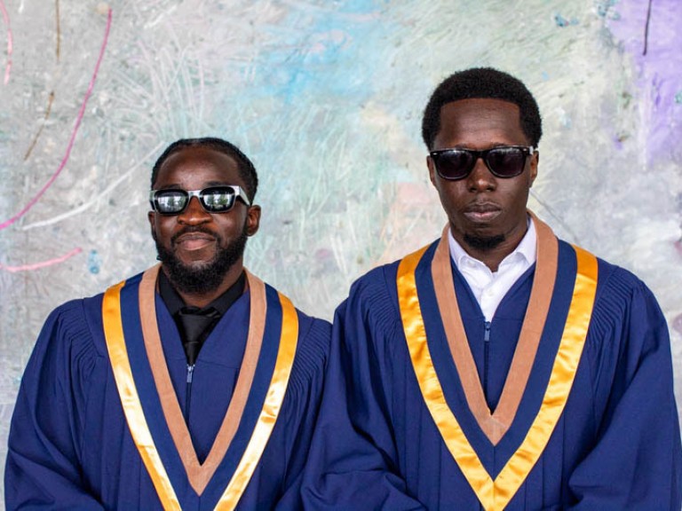 Two graduates wearing sunglasses pose for camera