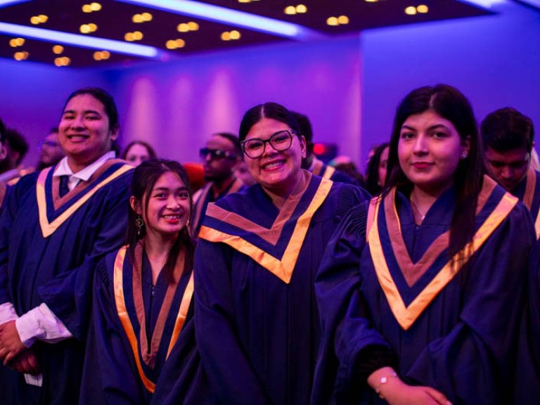 Graduates in ceremony audience smile for camera