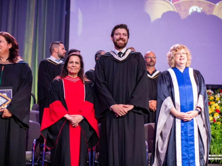Humber faculty and honorary degree recipient stand on stage