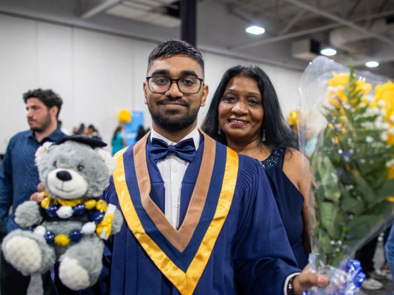 Graduate holds teddy bear and flowers