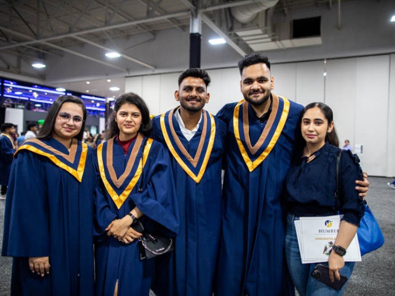 Four graduates take photo with ceremony guest